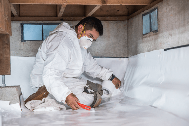 Crawl Pros professional installing protective material for a crawl space encapsulation