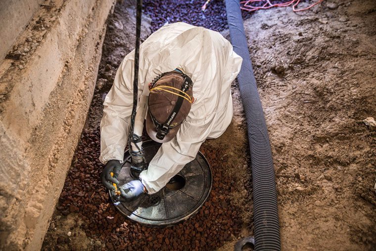Crawl Pros professional installing a new sump pump in a crawl space