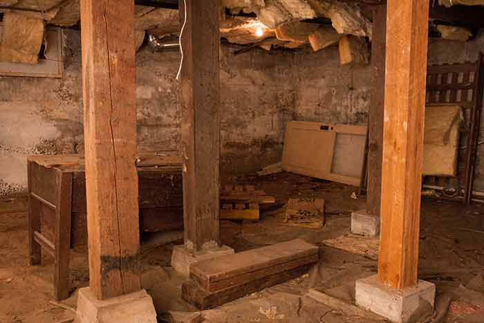 A crawl space with debris and material that needs to be removed