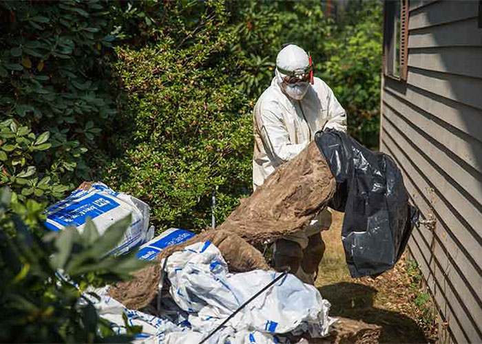 Crawl Pros professional removing old material from the side of a house from a crawl space cleanout