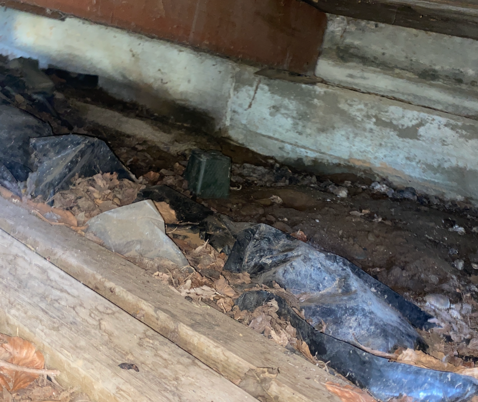 Crawl space in need of a crawl space cleanout littered with old material and debris